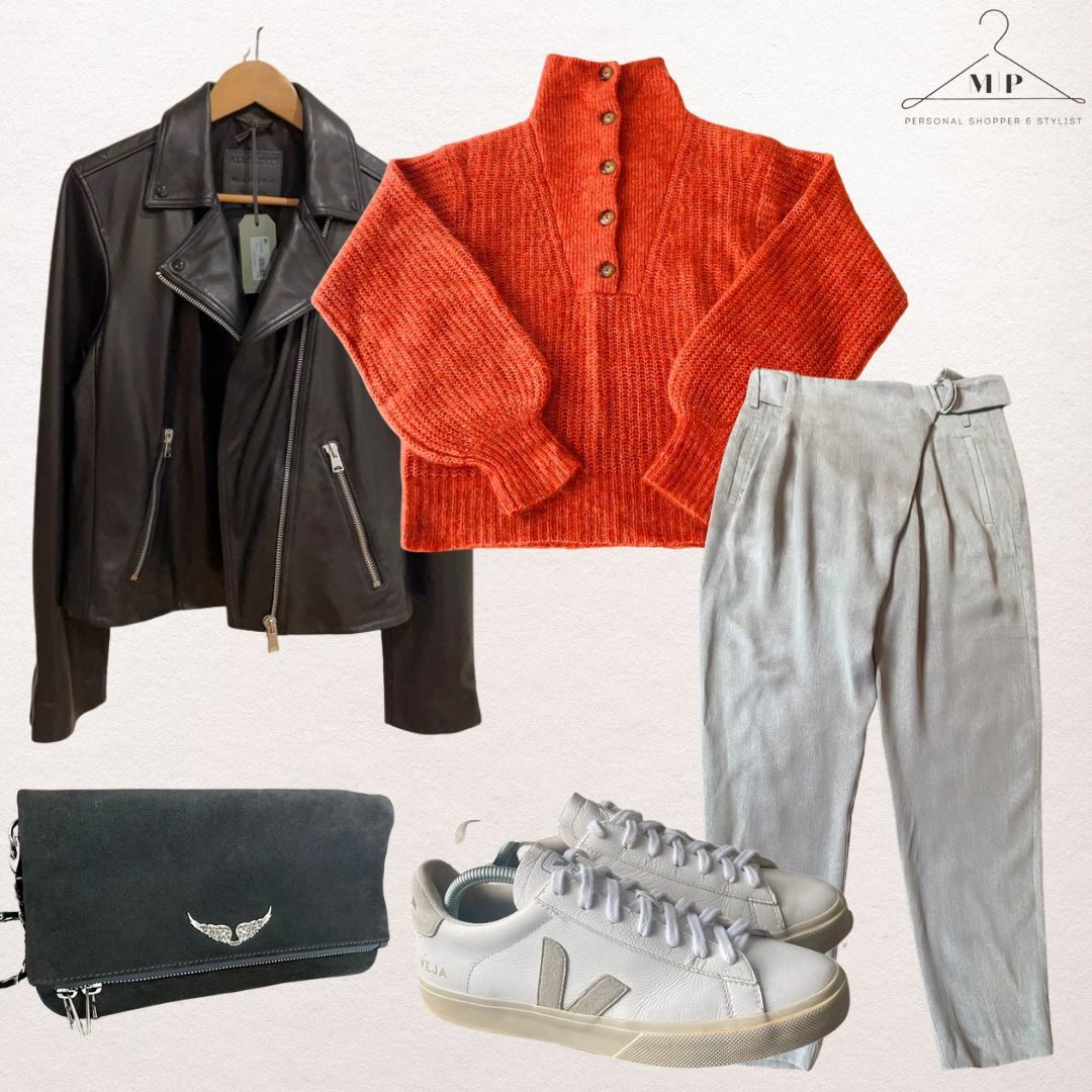 Black leather biker jacket with a rust ribbed half-zip jumper, grey linen tapered trousers, a black suede clutch and white leather trainers