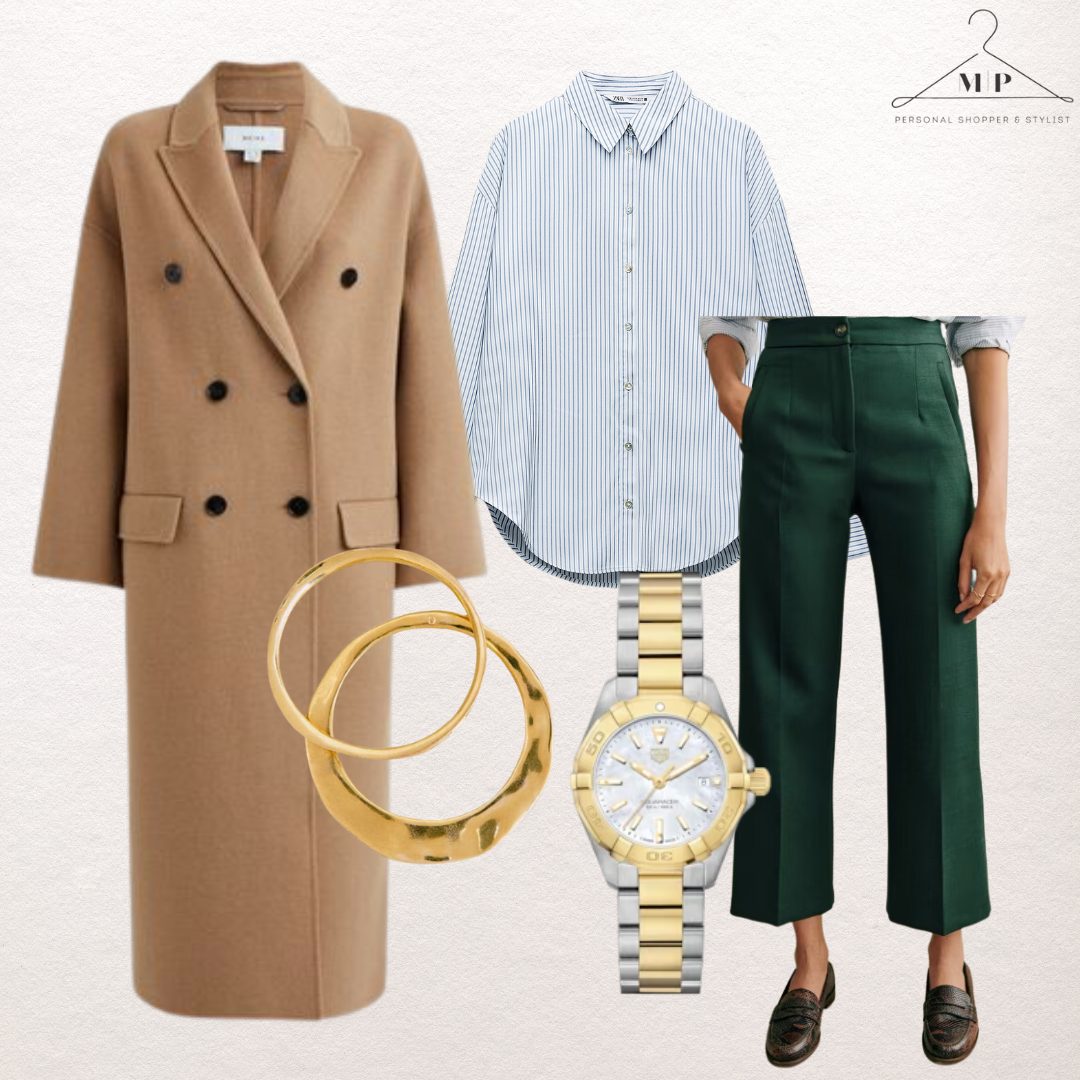 Camel double-breasted wool coat with a blue striped shirt, green cropped tailored trousers, chunky gold bangles, a two-tone watch and brown loafers